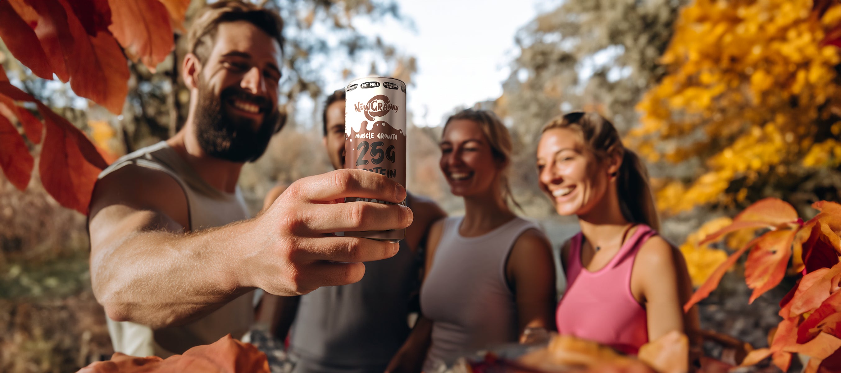 Przyjaciele w trakcie rozmowy na temat napojów newgranny. Zachwycają się smakiem napoju i prezentują go na wprost kamery. Dookoła jesienne liście. Uśmiechy wskazują na bardzo smaczny smak napojów